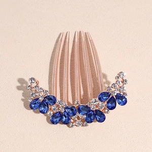 Detailed shot of rose gold hair comb featuring blue teardrop gems and clear rhinestones