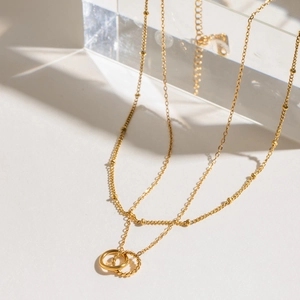Double-layered gold necklace with interlocking rings and cable chain detail