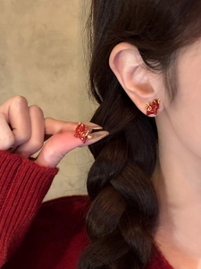 Close-up of red enamel dragon stud earrings worn by a model in a warm festive setting