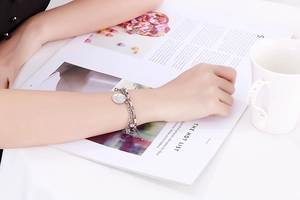 Close-up of double-layer stainless steel chain bracelet with a coin pendant on a woman