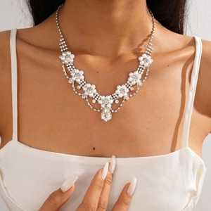 Close-up of diamond floral necklace featuring a large water drop pearl pendant charm