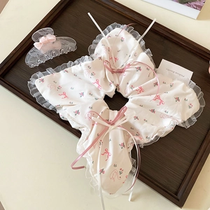 Détail du chouchou floral avec nœuds roses, bordure en dentelle et longs rubans
