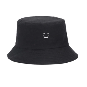 Black reversible fisherman hat with white embroidered smiley face and cow print pattern