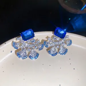 Elegant fan-shaped sterling silver earrings with blue rectangular gems and pavé crystals