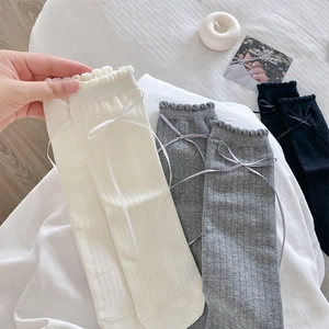 Detail of lace trim and ribbon bows on white, grey, and black cotton crew socks