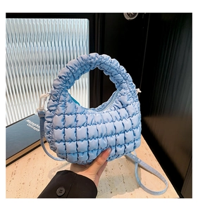 Detailed view of light blue quilted puffer handbag with soft texture and crossbody strap