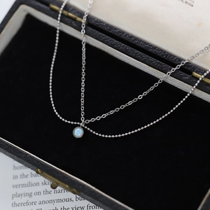 Close-up of double-layer silver chain featuring a vibrant round blue opal pendant