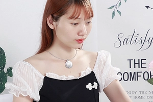 Detail showing a silver vintage round pendant necklace with engraved patterns on a model
