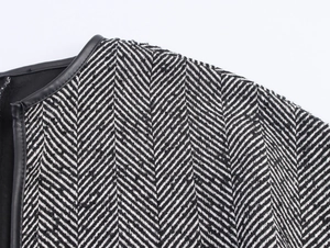Detail of black and white herringbone fabric coat with premium leather piping on the shoulder