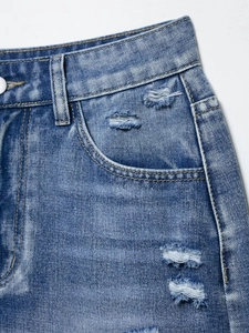 Detail of distressed denim shorts showing ripped texture and vintage blue wash effect