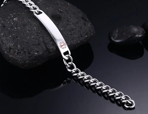 Dettaglio del bracciale medico in acciaio con croce rossa su pietre nere naturali