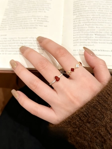 Detail shot of two 18k gold-plated gourd rings with red heart stone on a model hand