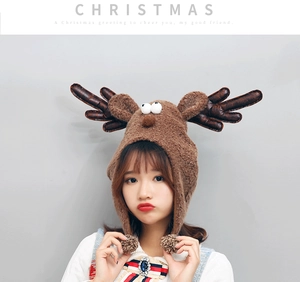 Brown plush reindeer Christmas hat with antlers and pom-poms worn by a model