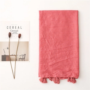 Detailed macro view of coral pink linen scarf texture and handmade tassel fringe detail