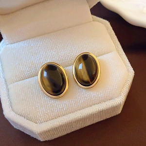 Macro shot of vintage oval tiger eye stud earrings in gold plating on velvet cushion