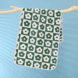 Detail of soft coral fleece towel with green checkered floral pattern on wooden branch