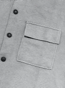 Detailed close-up of grey twill jacket featuring cargo flap pocket and matte black buttons