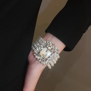 Macro detail of multilayer pearl bracelet featuring a large square crystal center stone