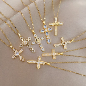 Collection of gold cross necklaces with zircon inlays displayed on beige silk fabric