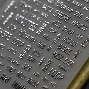 Macro shot of 3D embossed silver metallic letter nail stickers with various English words