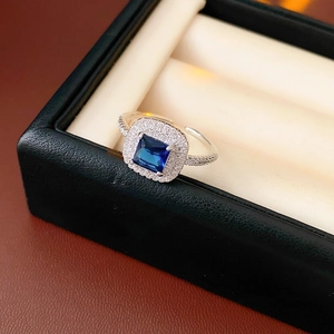 Detail showing square-cut blue gemstone ring with pave diamonds on silver band