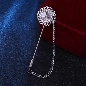 Macro shot of silver sunflower lapel pin with crystal center and metal tassel chain