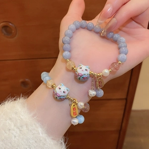 Detail of beaded Maneki Neko bracelets with natural pearls and lucky charms on wrist