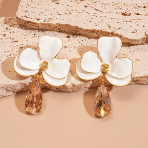Détail de boucles d'oreilles fleurs avec pétales blancs et cristal goutte d'eau champagne