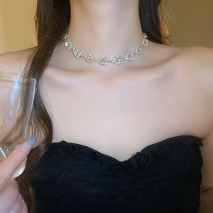 Close-up of a silver rhinestone heart necklace on neck, highlighting elegant luxury style