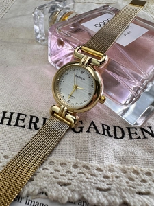 Detailed macro view of a gold mesh band watch with a sparkling rhinestone dial design