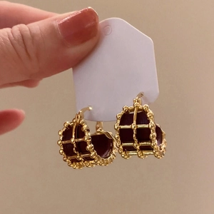Close-up of gold plated round hoop earrings with dark red leather inlay detail