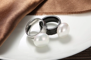 Detail of hammer-textured pearl rings in black and silver on white ceramic plate