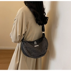 Detail view of dark grey denim hobo bag worn by model showing its stylish half-moon shape