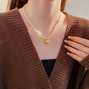 Detail of a pearl necklace with a gold fortune bag pendant worn on a model's neck