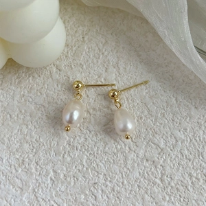 Detail of elegant gold drop earrings featuring white baroque freshwater pearls