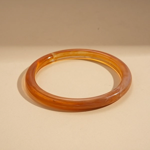 Macro detail of amber orange translucent acrylic resin bracelet with natural texture