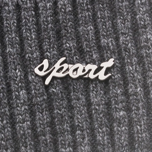 Macro shot of knitted texture with sport metal logo on grey winter wool beanie hat