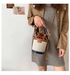 Detail of canvas bucket bag with leather patchwork and drawstring closure in studio setting
