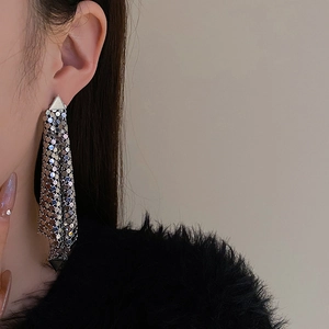 Close-up of long silver fringe tassel earrings with mesh triangle design on model