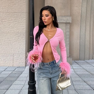 Détail du cardigan rose avec poignets en plumes et boucle en métal en forme de cœur