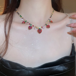 Luxurious gold necklace featuring colorful gemstones and red heart-shaped fringe pendants