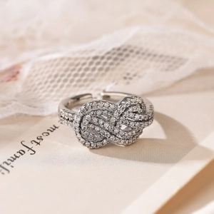 Macro shot of silver-tone knot ring with pavé-set cubic zirconia on a romantic lace background