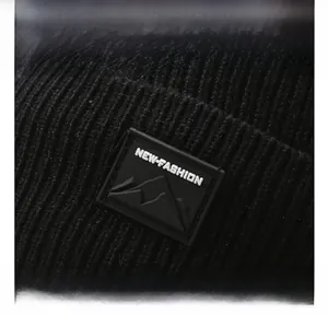 Close-up of black knit beanie with NEW-FASHION mountain logo and thick texture