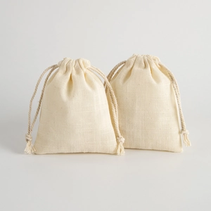 Two natural beige linen drawstring pouches for jewelry storage with fabric texture on white background