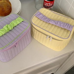 Detailed view of quilted makeup bags with ruffled handles in lavender and pale yellow