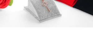 Gros plan d'un pendentif clé en or rose avec zircons sur un support en velours gris