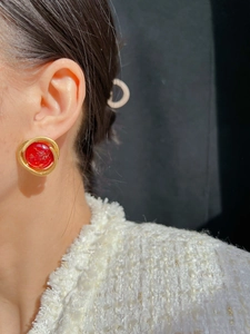 Close-up of vintage gold spiral red drop earrings worn on ear with professional lighting