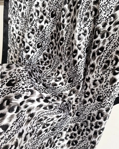 Detailed macro view of leopard print satin fabric with smooth silk-like texture and sheen