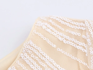 Detail of champagne sequins and fine mesh fabric on the shoulder of the dress