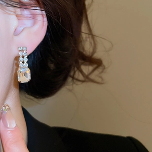 Close-up of a vintage emerald-cut gemstone earring with double-row diamond accents on a model